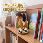 A crocheted pony toy sits on a wooden bookshelf in a nursery-like setting, with children's books around it and decorative text reading 'My Darling Crochet Pony' and 'Handcrafted Nursery Magic.' Because a real environment is visible, this is Lifestyle rather than Product/Packaging.