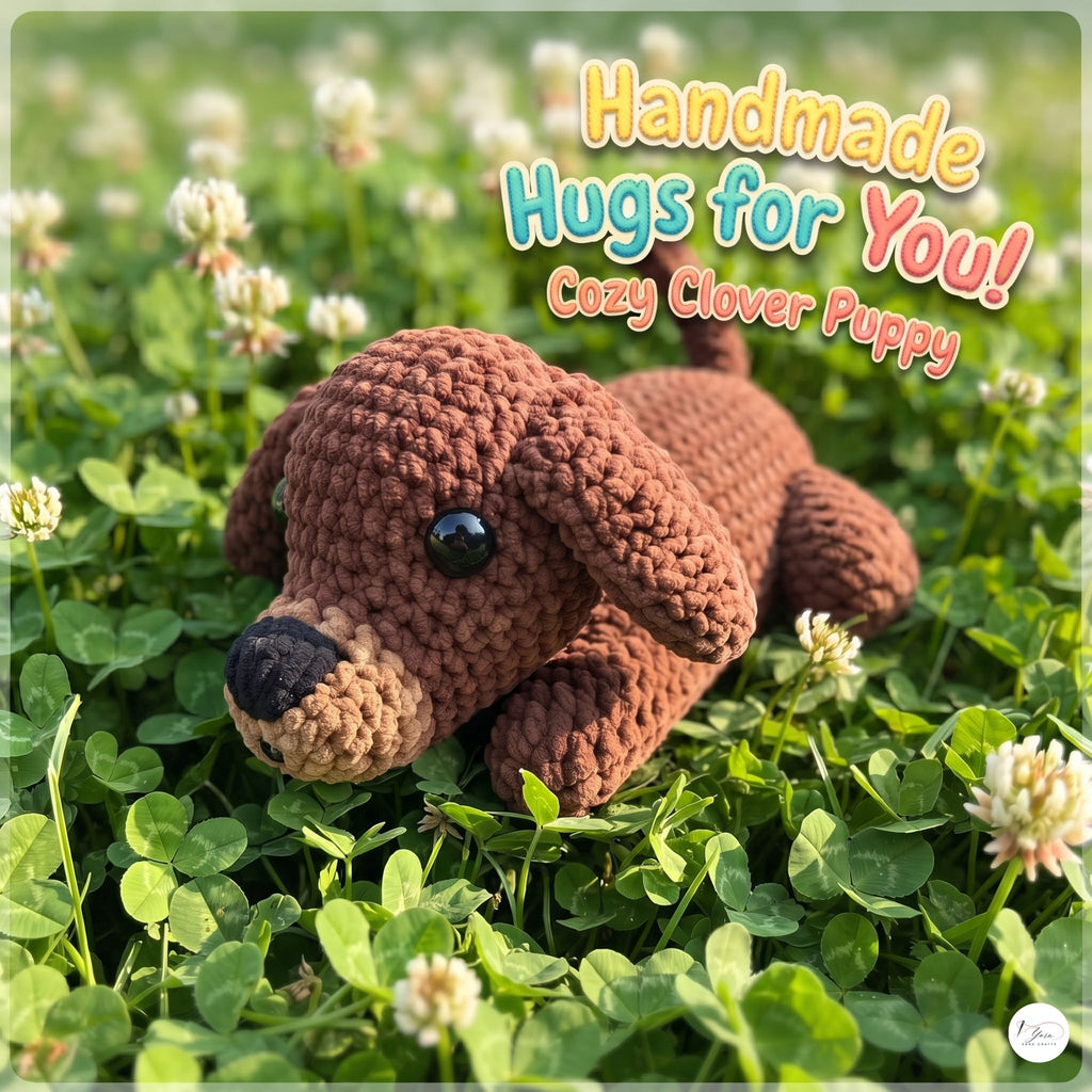 A handmade crocheted puppy toy lying on green clover with white flowers. The text overlay reads 'Handmade Hugs for You! Cozy Clover Puppy'.