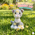 A crocheted cat toy sits on green grass outdoors, with blurred flowers and trees in the background. Text in the upper right reads 'SWEETHEART CROCHET CAT GALICO AMIGURUM!'.