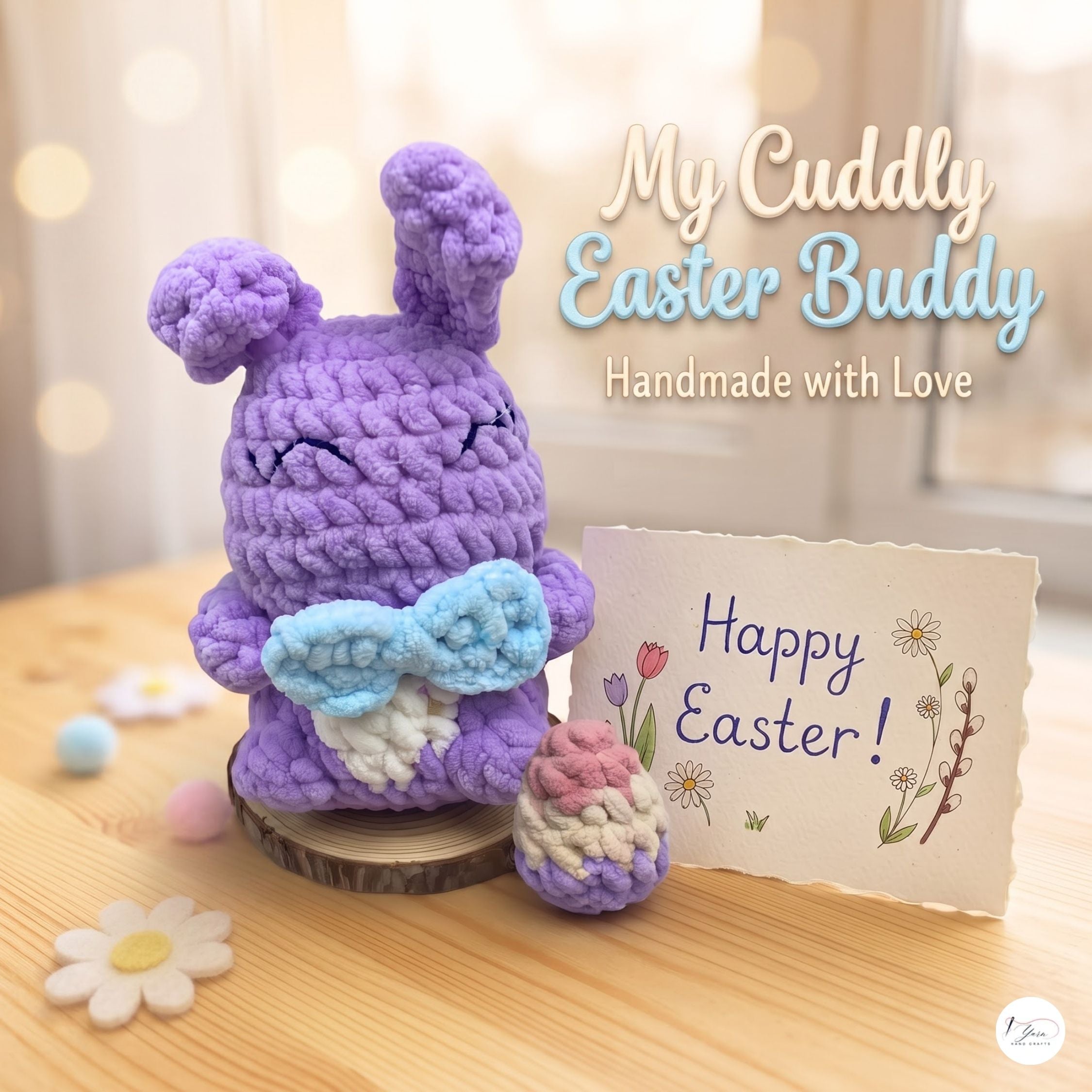 A crocheted purple bunny Easter bunny figure holding a light blue bow and white pouch, displayed on a wooden surface beside a handmade 'Happy Easter!' card and a small pink-and-white cupcake decoration. Text on the image reads 'My Cuddly Easter Buddy Handmade with Love.