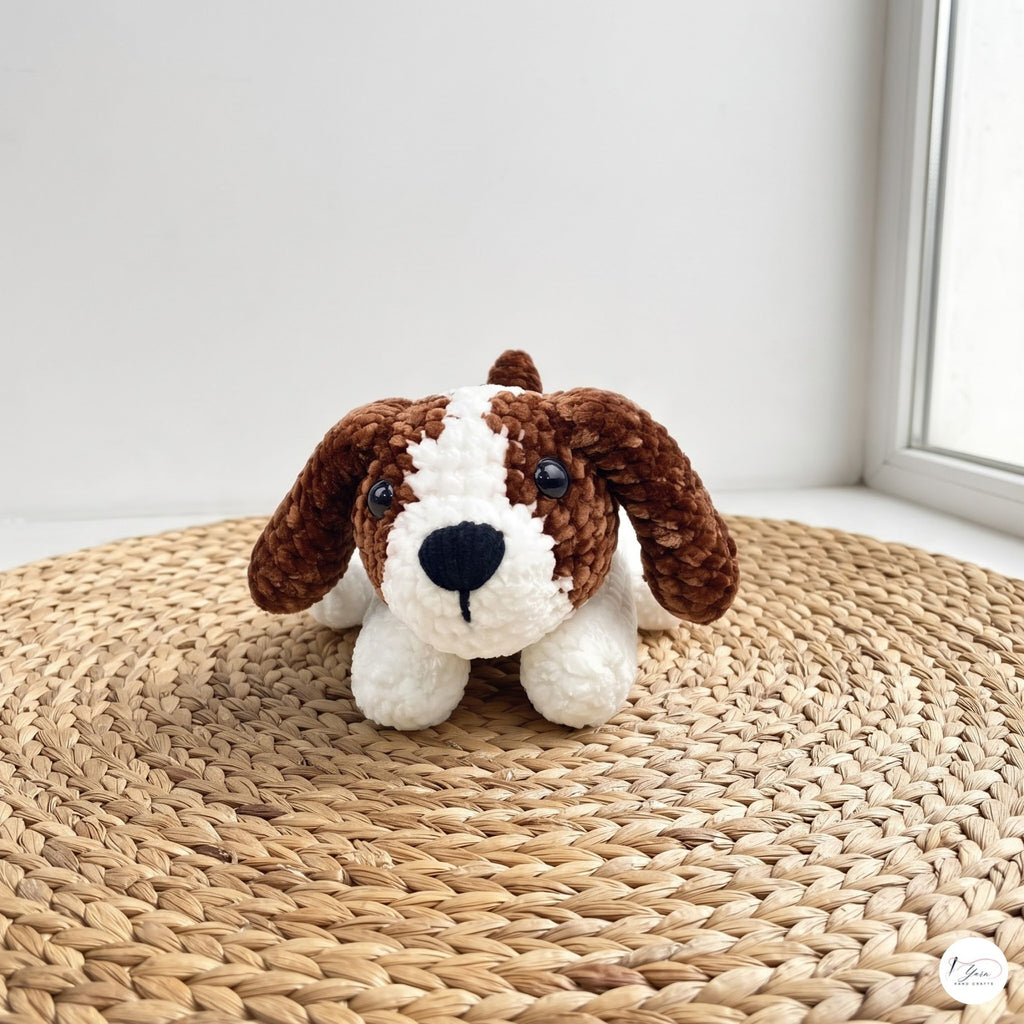 A crocheted dog toy with brown and white yarn, sitting on a round woven straw mat near a window.