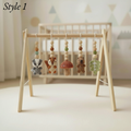 A wooden baby mobile toy stand with five hanging crocheted animal and nature charms, shown in a softly styled nursery setting with a crib blurred in the background. The text 'Style 1' appears in the top left corner.