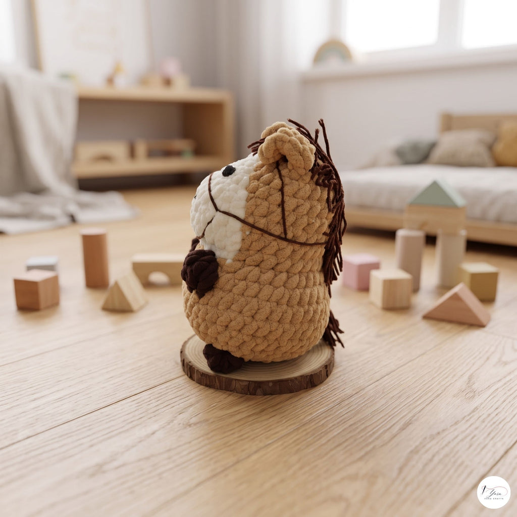 A small crocheted plush horse toy sits on a round wooden slice coaster on a light wood floor, surrounded by wooden blocks in a softly blurred nursery or playroom setting.