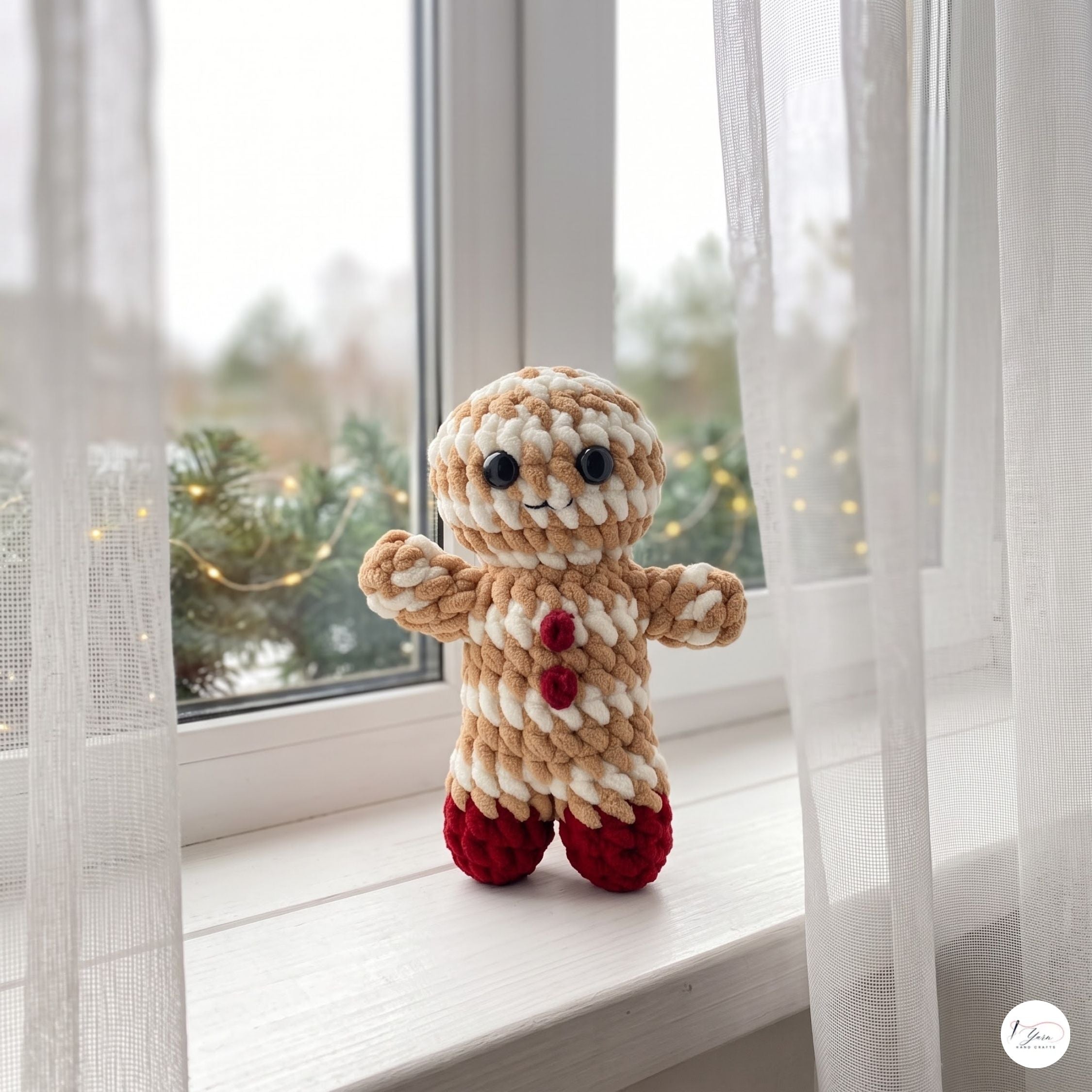 A handmade crocheted gingerbread man doll with beige and white yarn body, red yarn buttons, and red yarn feet, standing on a white windowsill with sheer curtains and a blurred window view in the background.