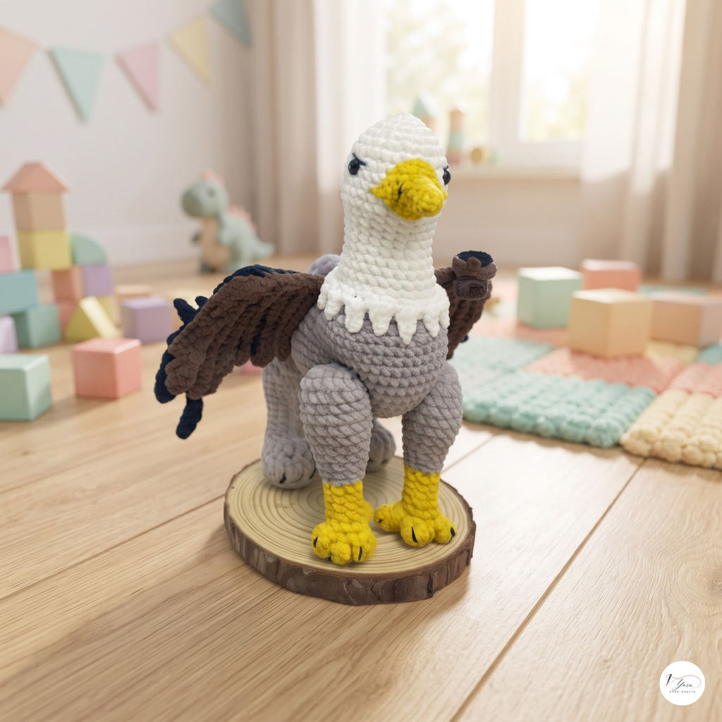 A crocheted eagle toy standing on a round wood slice base, photographed in a softly lit children's room with pastel blocks and toys blurred in the background.