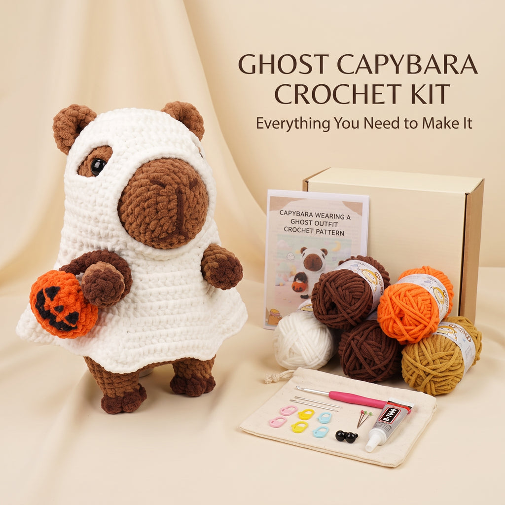 A crocheted capybara doll dressed in a white ghost outfit and holding an orange pumpkin, shown with a crochet kit box, yarn balls, a pattern booklet, and tools on a beige fabric background. Text reads 'GHOST CAPYBARA CROCHET KIT' and 'Everything You Need to Make It.