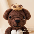 A close-up of a crocheted brown bear plush toy wearing a beige cookie on its head, with a white heart at the chest and the text 'ADORABLE COOKIE DETAIL' in the lower right corner.