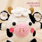 A close-up of a crocheted cow plush toy with black and white patches, a pink nose and cheeks, brown horns, and black bead eyes. The text 'ADORABLE DETAILS' appears in the top right corner against a soft beige fabric background.