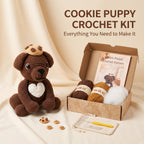 Cookie Puppy Crochet Kit displayed on a beige fabric backdrop, featuring a crocheted brown puppy with a white heart, yarn balls, a crochet hook, a pattern booklet, and small cookie pieces arranged beside an open kraft box with the text 'COOKIE PUPPY CROCHET KIT' above.