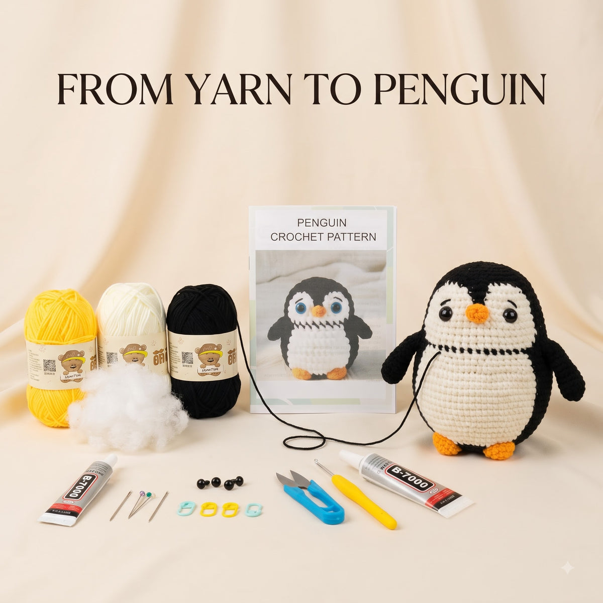 Crochet penguin kit displayed on a beige fabric backdrop with the text 'FROM YARN TO PENGUIN' at the top. The kit includes a finished crocheted penguin, a crochet pattern booklet, three balls of yarn in yellow, cream, and black, stuffing, tweezers, beads, scissors, and adhesive tubes.