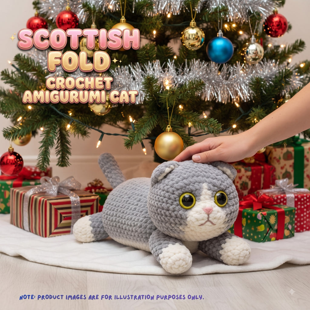 A crocheted amigurumi cat plush toy in gray and white is shown lying on a white blanket under a decorated Christmas tree, with a human hand touching its head. Gift boxes are around it, and large text reads 'SCOTTISH FOLD CROCHET AMIGURUMI CAT'.
