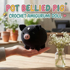 A black crocheted pig doll with a pink snout sits on a person's hand on a wooden table, with a small glass vase of white flowers in the foreground and large text reading 'POT BELLIED PIG CROCHET AMIGURUMI DOLL' at the top.
