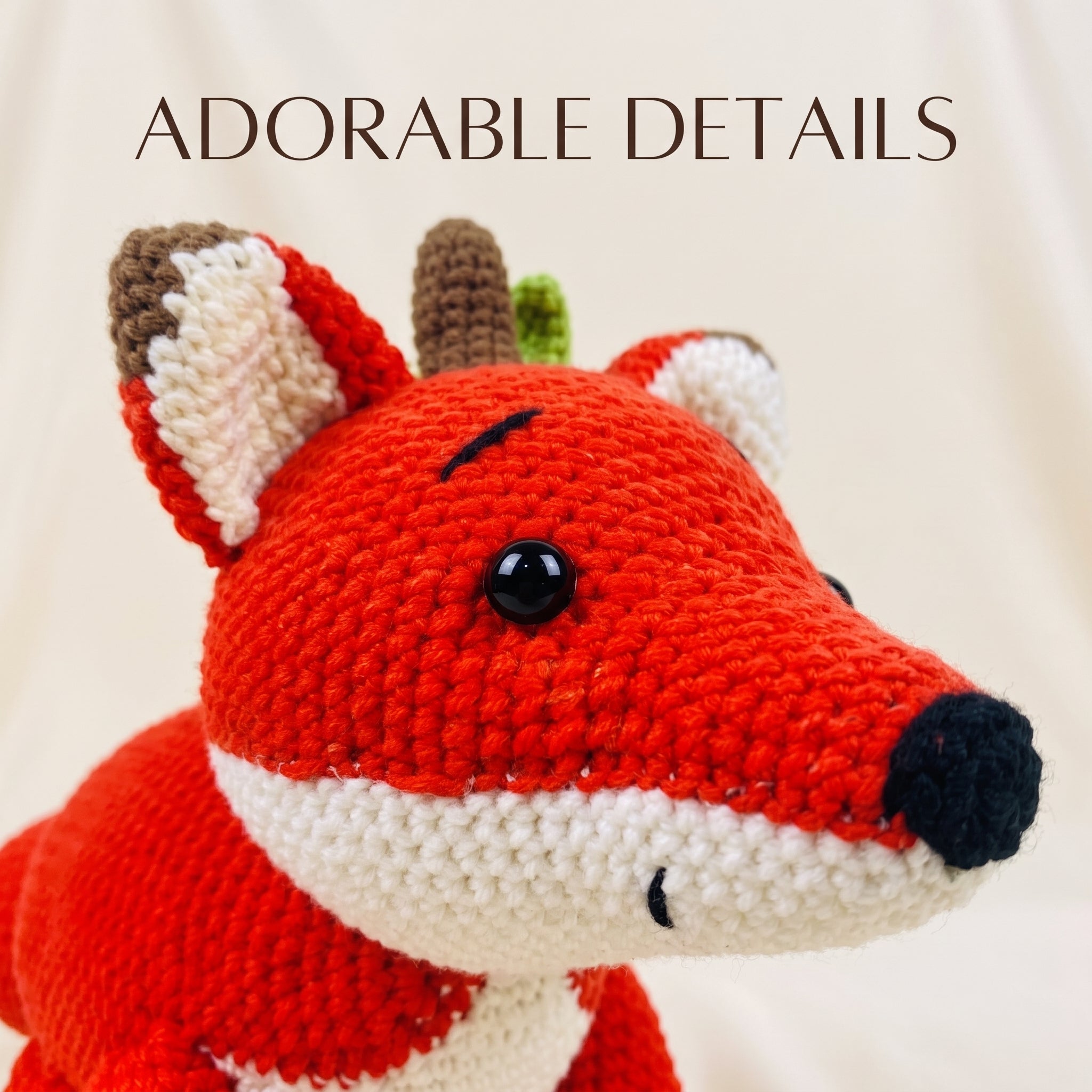A close-up of a crocheted fox toy with bright red, white, cream, brown, and black details, shown against a soft cream background with the text 'ADORABLE DETAILS' at the top.