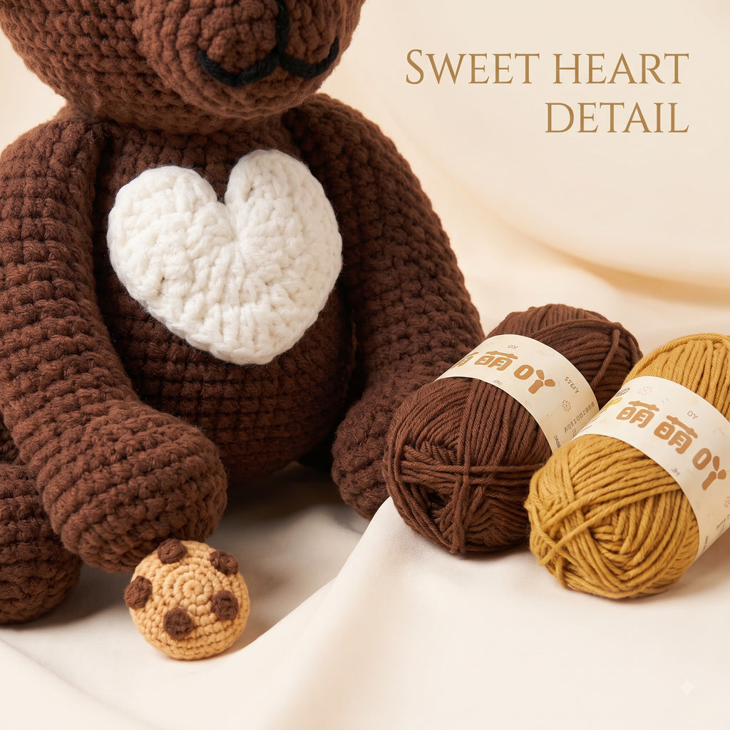A crocheted brown bear plush toy with a white heart on its chest, shown with two balls of yarn in brown and mustard yellow and a small cookie-shaped accessory. The text 'SWEET HEART DETAIL' appears in the upper right on a soft cream fabric background.