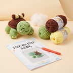 Crocheted turtle toy with a step-by-step guide booklet and crochet hook, shown alongside yarn balls in green, brown, and yellow on a beige background.