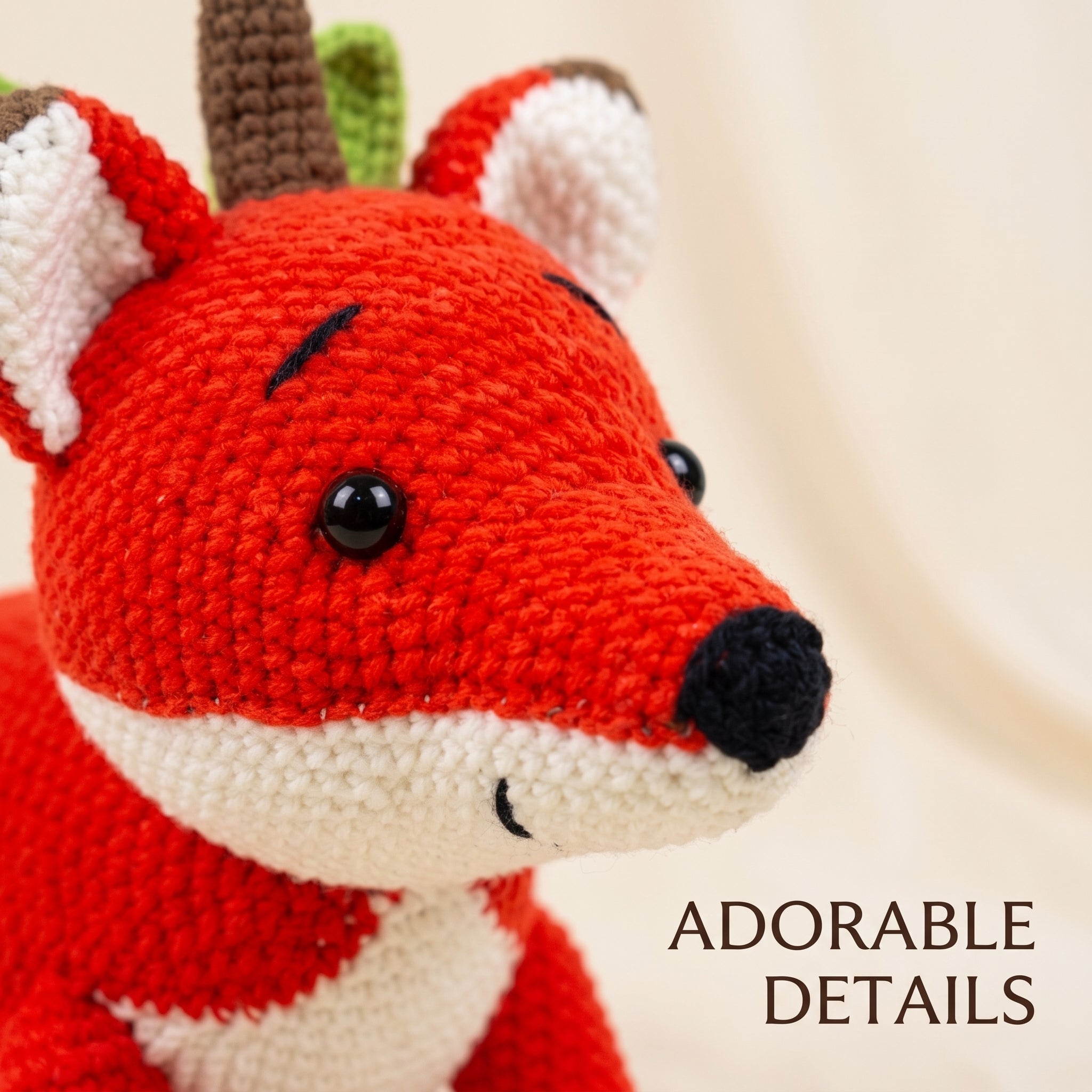 Close-up of a crocheted fox toy with bright red, white, brown, and green details, shown against a soft cream background with the text 'ADORABLE DETAILS' in the lower right.
