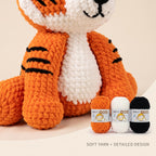 Crocheted amigurumi tiger plush toy in orange, white, and black yarn, shown with three small yarn balls labeled 'Soft Yarn' on a light beige background. Text at the bottom reads 'SOFT YARN • DETAILED DESIGN'.