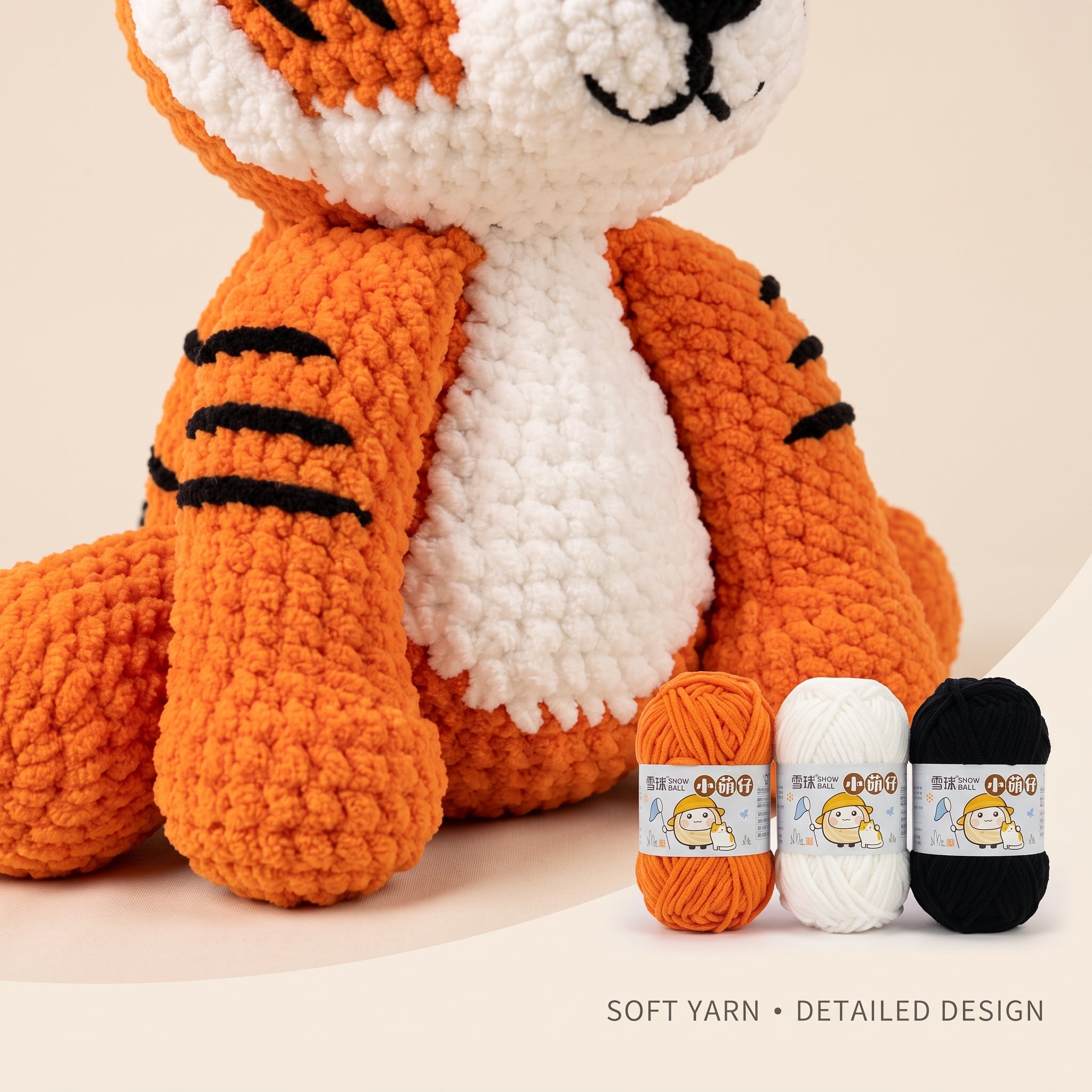 Crocheted amigurumi tiger plush toy in orange, white, and black yarn, shown with three small yarn balls labeled 'Soft Yarn' on a light beige background. Text at the bottom reads 'SOFT YARN • DETAILED DESIGN'.