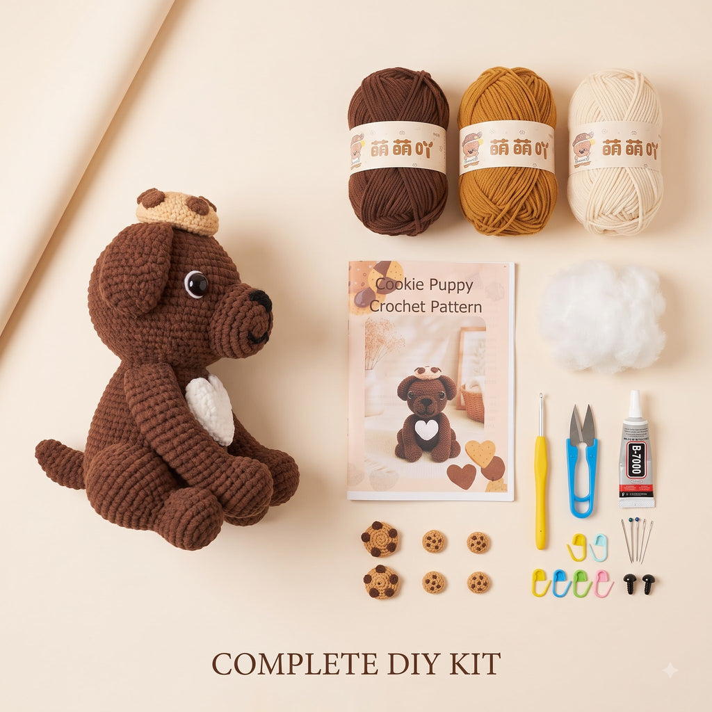 A crocheted dog DIY kit laid out on a warm beige background, including a brown crochet dog toy, three balls of yarn in brown, mustard, and cream, a crochet pattern booklet, white fiber, a yellow hook, blue and yellow scissors, a glue stick, small wooden cookie pieces, and colorful needle cases. Text at the bottom reads 'COMPLETE DIY KIT'.