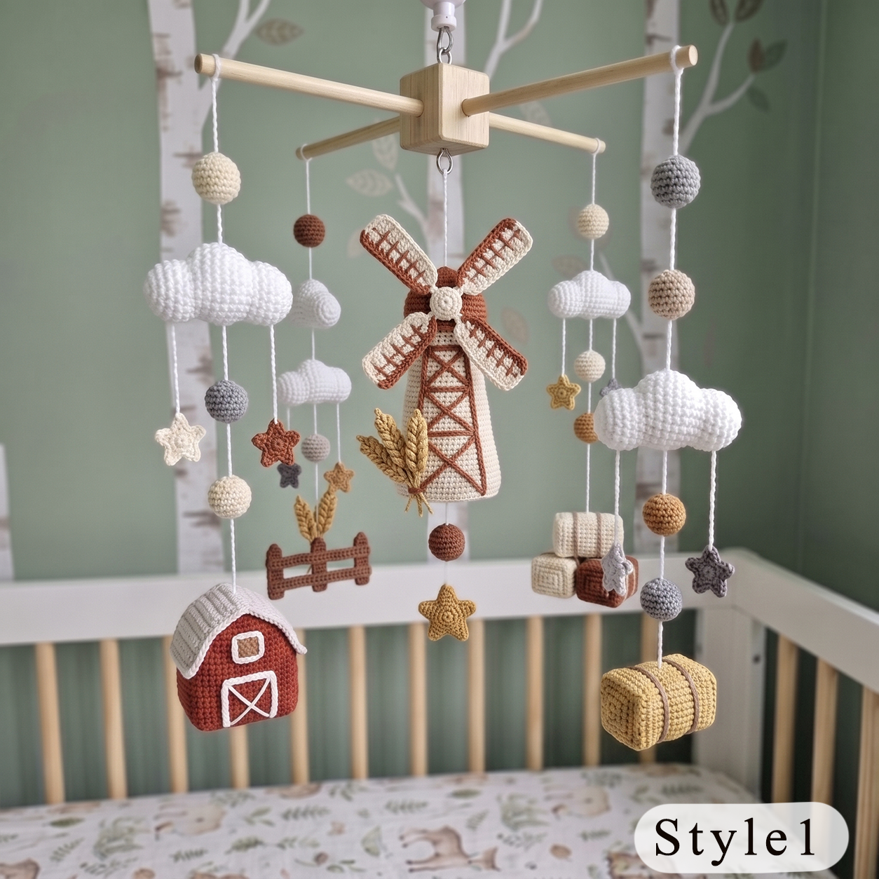 A crocheted baby mobile with a farm theme, hanging above a crib. The mobile features a wooden crossbar, white yarn clouds, a central windmill, a red barn, wheat stalks, stars, fence pieces, and hay bales in earthy brown, beige, and white tones.