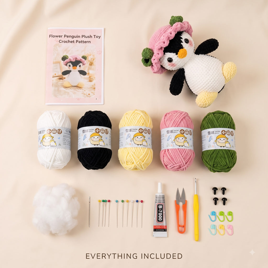 A flat lay of a crocheted flower penguin plush toy kit on a beige background, including a finished penguin plush wearing a pink flower crown, a crochet pattern card, five balls of yarn in white, black, yellow, pink, and green, stuffing, needles, scissors, thread, and small accessories. Text at the bottom reads 'EVERYTHING INCLUDED'.