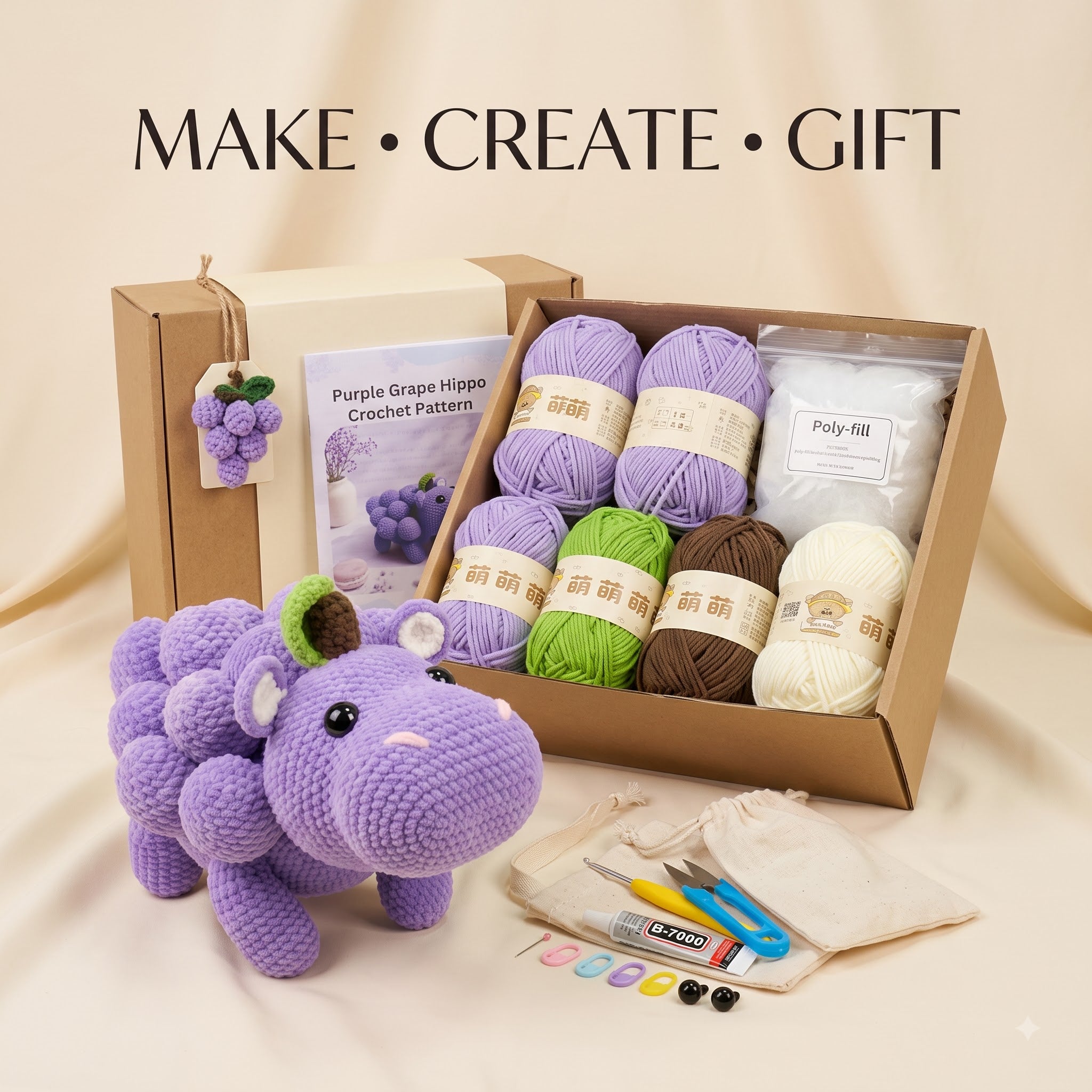 Crochet gift kit with a purple grape hippo plush toy, an open box of yarn balls, a crochet pattern booklet, poly fill, scissors, beads, and a drawstring bag on a beige fabric background. Text at the top reads 'MAKE • CREATE • GIFT'.