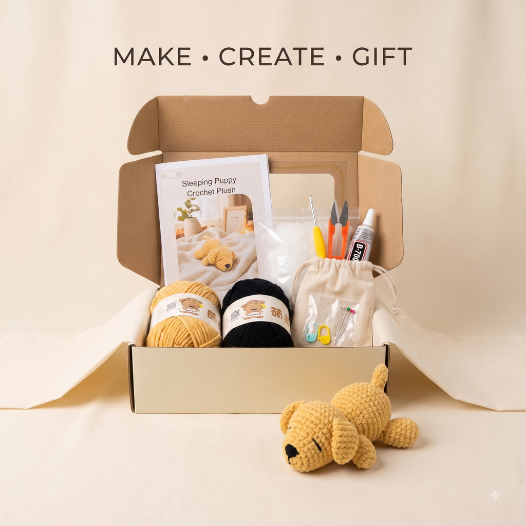 An open kraft cardboard gift box on a cream background, filled with crochet supplies and a small plush toy. Visible items include a crochet puppy plush instruction sheet, two balls of yarn in mustard yellow and black, a small drawstring pouch, and crochet hooks and thread.