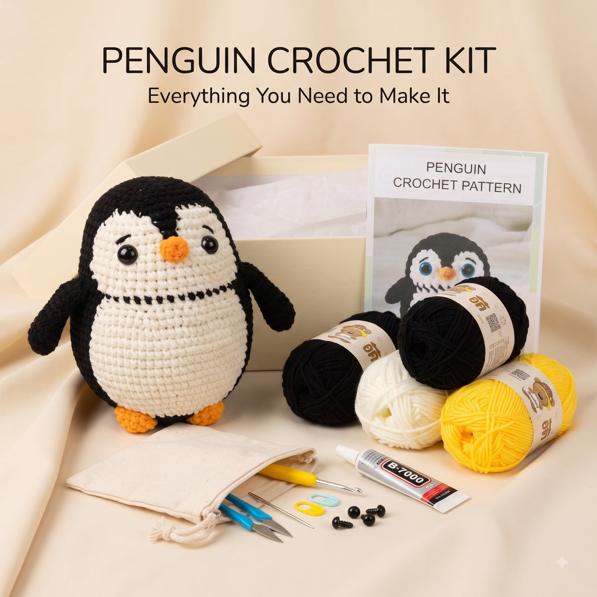 Penguin crochet kit arranged on a beige fabric background, including a crocheted penguin, yarn balls in black, cream, and yellow, a crochet pattern card, a small pouch, and tools. Text at the top reads 'PENGUIN CROCHET KIT' and 'Everything You Need to Make It'.
