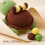 Close-up of a crocheted turtle toy with a brown shell, green body, and yellow-and-brown striped tail, styled on beige paper with small yarn balls and the text 'SHELL DETAILS'.