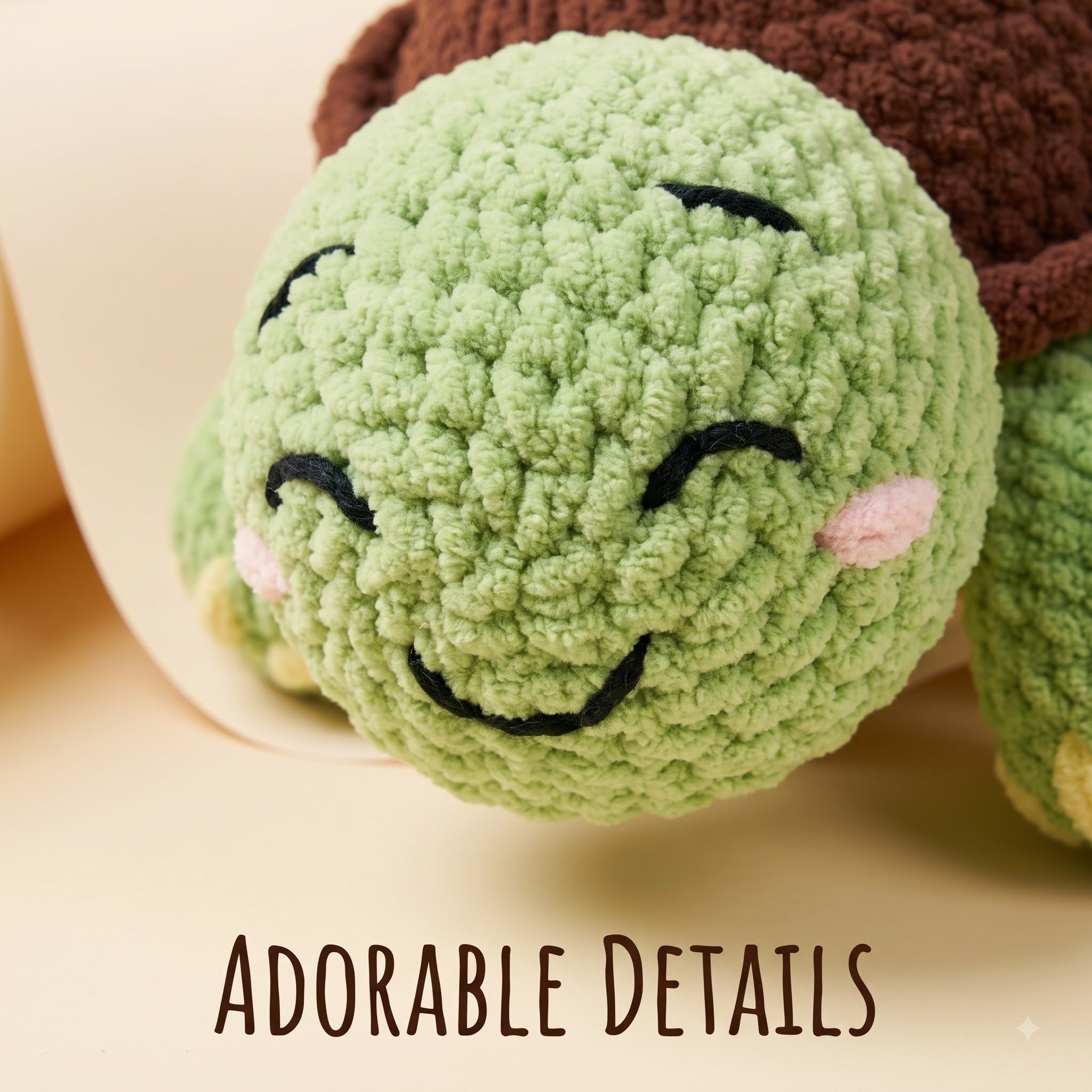 A close-up of a crocheted plush turtle toy with a light green face, black embroidered closed eyes and smile, pink cheeks, and a dark brown shell. The words 'ADORABLE DETAILS' appear at the bottom.