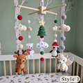 Crocheted baby crib mobile with hanging plush toys including a brown reindeer, white polar bear, black-and-white penguin, cream fox, green Christmas tree, cream clouds, and red/gray pom-poms, displayed above a crib in a nursery.