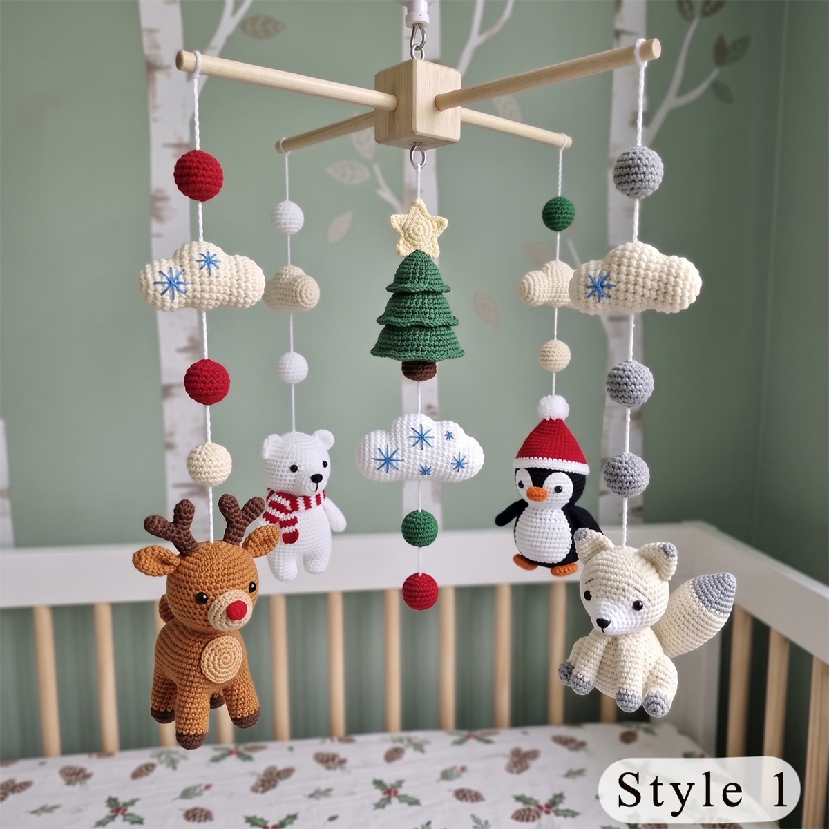 Crocheted baby crib mobile with hanging plush toys including a brown reindeer, white polar bear, black-and-white penguin, cream fox, green Christmas tree, cream clouds, and red/gray pom-poms, displayed above a crib in a nursery.