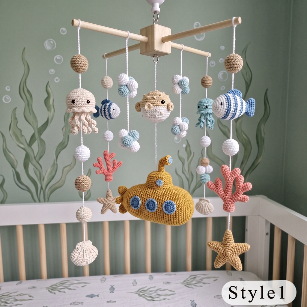 Crocheted baby mobile with sea-themed plush toys including a yellow submarine, octopus, fish, starfish, and coral, hanging over a crib against a green wall with sea plant illustrations.