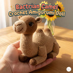 A crocheted camel doll in warm tan and brown yarn is being held in a person's hand over a wooden table, with sunflowers in the background and the text 'Bactrian Camel Crochet Amigurumi Doll' at the top.