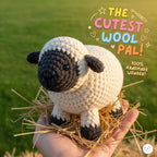 Handmade Valais Blacknose Sheep crochet amigurumi doll with a fluffy white fleece body, black face, black ears, and dark legs resting on straw held in a hand outdoors.