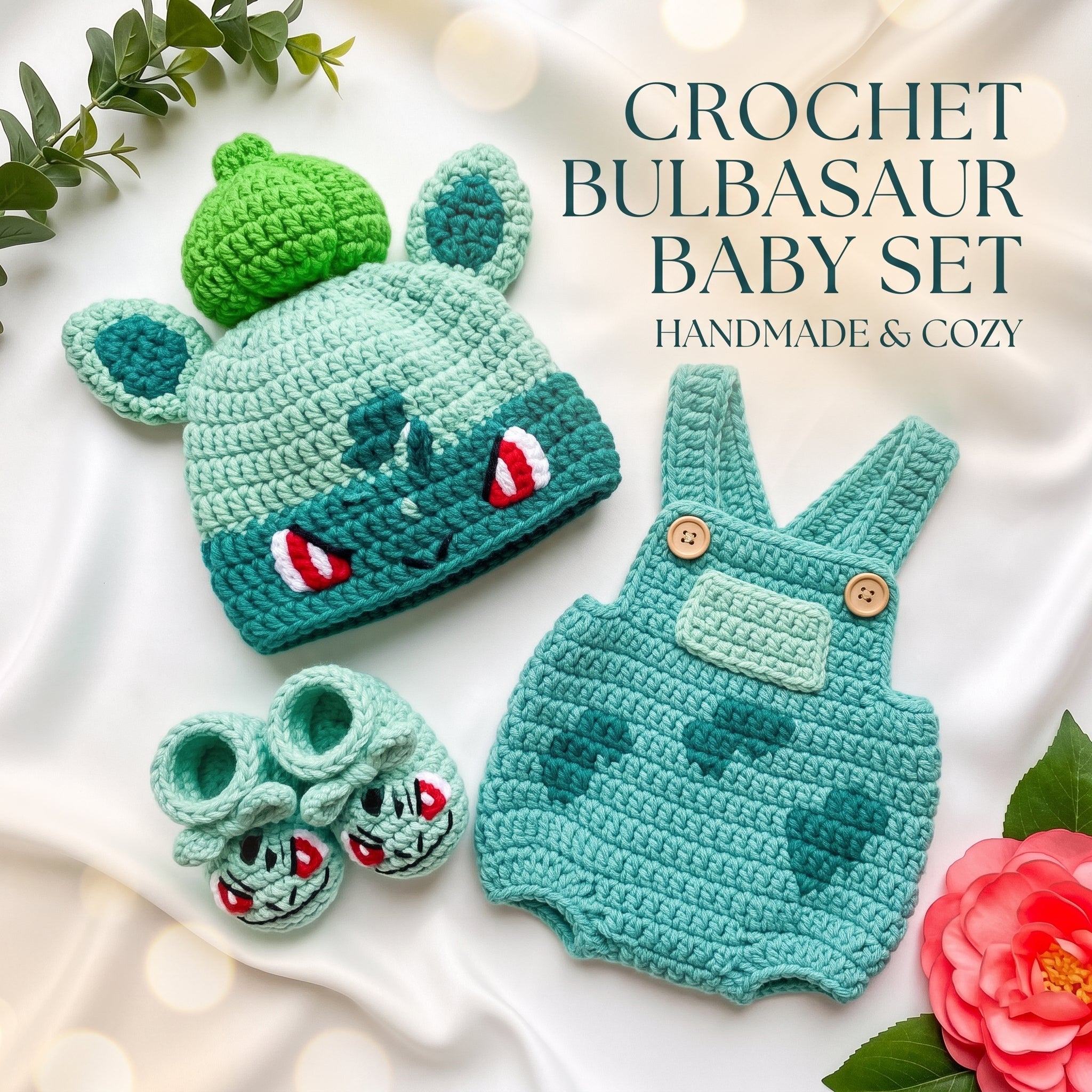 Crochet Bulbasaur baby set including a green and teal crocheted hat with bulb details, matching overalls, and booties, arranged on a white fabric background with decorative leaves and a flower.