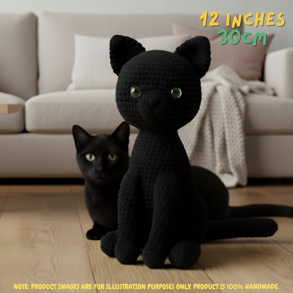 A black crocheted cat toy sits on a wooden floor in front of a real cat, with a beige sofa in the background. Text in the top right reads '12 INCHES 30CM' and a note at the bottom says the product images are for illustration purposes only.