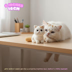 A white cat lies on a light wood desk next to a small crocheted cat toy. The scene is indoors with soft natural light, and a pink text overlay at the top left reads '6 INCHES 16CM'.