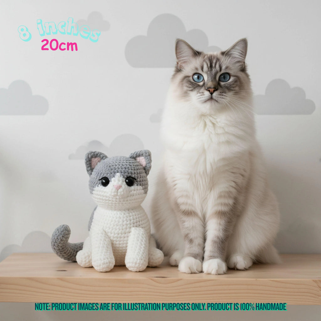 A fluffy white and gray cat sits next to a crocheted plush cat toy on a wooden surface against a light gray cloud-patterned wall. Text in the top left reads '8 inches 20cm', and a teal note at the bottom says product images are for illustration purposes only and the product is 100% handmade.