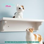 A white wall-mounted shelf with a crocheted calico cat toy displayed on top, with a real calico cat looking up at the shelf below. Text in the image indicates the shelf is 10 inches by 25 inches and notes the product is handmade.