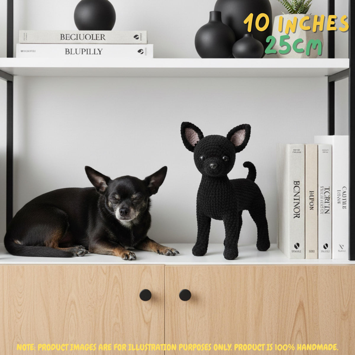 A black crocheted dog figurine stands on a white shelf next to a real black dog lying down, with books and black decorative vases on the shelf. Yellow text in the top right says '10 INCHES 25CM'.