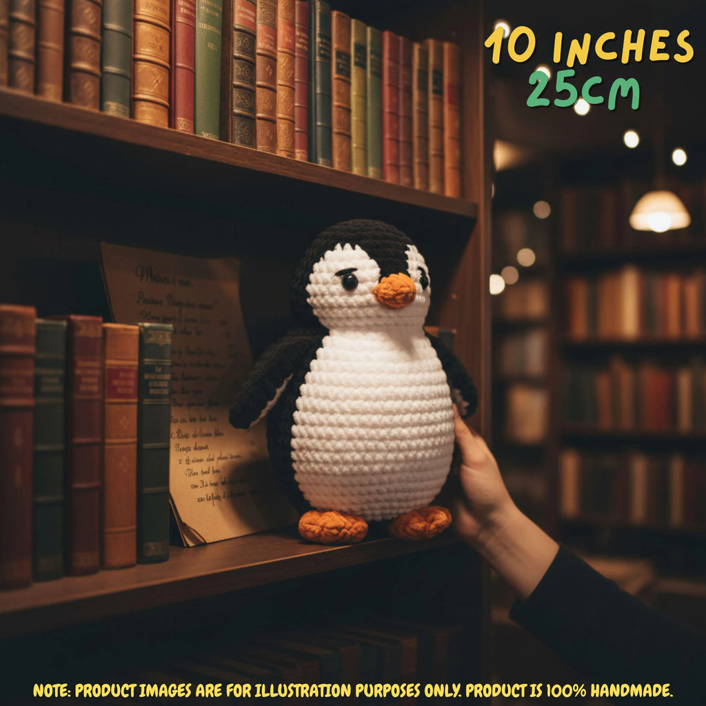 A crocheted penguin toy being held by a hand in front of a warm, blurred bookshelf. The text overlay reads '10 INCHES 25CM' and includes a disclaimer at the bottom stating the product image is for illustration purposes only.