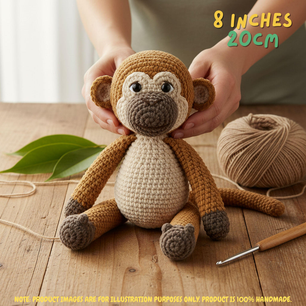 A crocheted plush monkey toy being held by two hands on a wooden table, with a ball of tan yarn, a crochet hook, and green leaves nearby. Text in the top right reads '8 INCHES 20CM' and a note at the bottom says product images are for illustration purposes only.