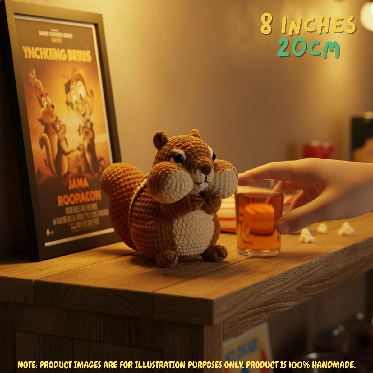 A crocheted squirrel plush toy sits on a wooden table beside a framed poster and a hand holding a glass of iced tea. Text in the corner reads 8 INCHES 20CM.