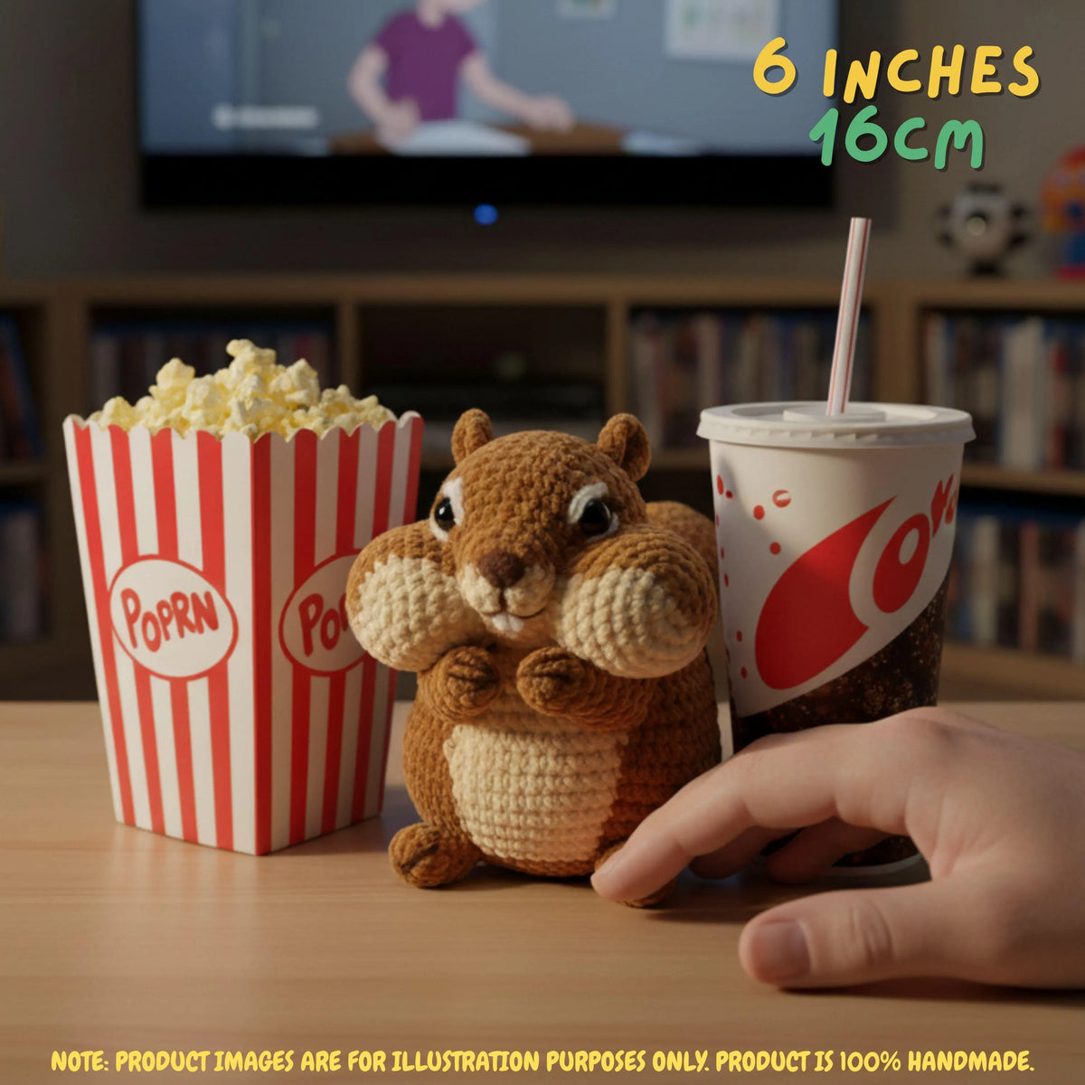 A crocheted squirrel toy sits on a tabletop next to a popcorn bucket, a drink cup, and a human hand, with text reading 6 inches 16cm and a note about the product being 100% handmade.