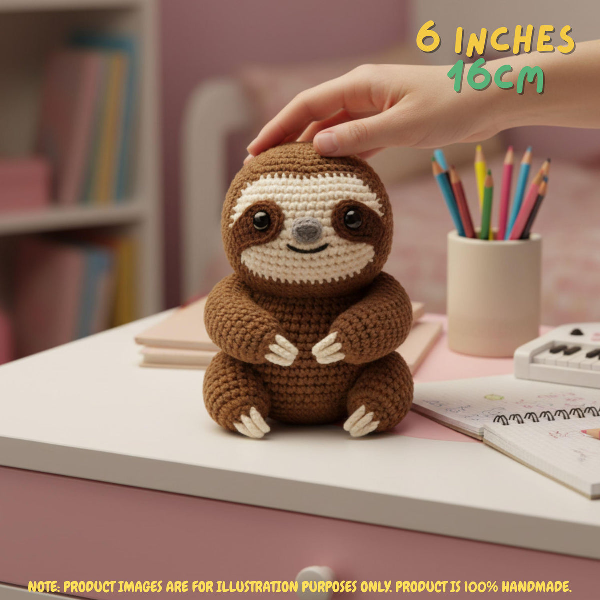 Handmade brown crochet sloth amigurumi doll sitting on a desk with a hand holding its head, featuring "6 INCHES / 16CM" text overlay.