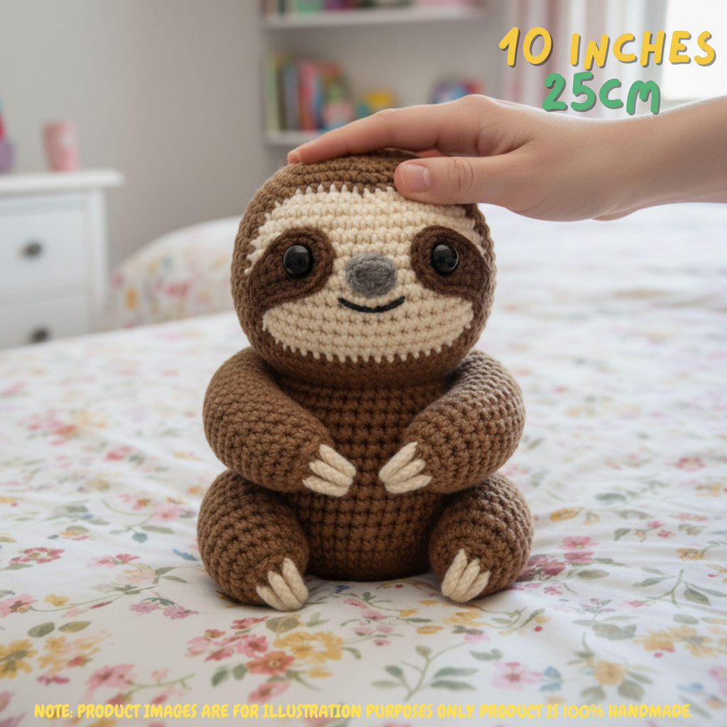 Handmade brown crochet sloth amigurumi doll sitting on a floral bed with a hand gently resting on its head, featuring "10 INCHES / 25CM" text overlay.