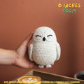 A hand holds a small crocheted owl toy against a warm terracotta wall. The text '6 INCHES 16CM' appears in the top right, and a note at the bottom says the product image is for destination purposes only and the product is 100% handmade.