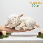 Handmade cream-colored crochet baby lamb amigurumi doll in a sleeping pose resting in hands over a candlelit background with "12 INCHES / 30CM" text overlay.