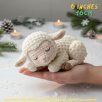 Handmade cream-colored crochet baby lamb amigurumi doll in a sleeping pose held in a hand over a cozy candlelit background with "6 INCHES / 16CM" text overlay.